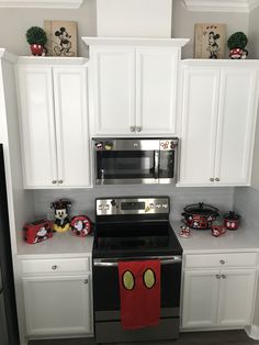 a kitchen with white cabinets and mickey mouse magnets on the stove top oven door