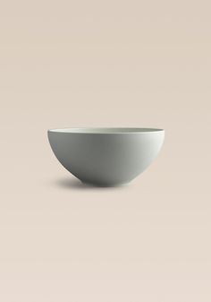 a white bowl sitting on top of a table next to a brown and beige wall