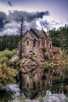 an old building sitting on top of a hill next to a lake