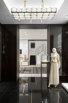 a statue in the middle of a room with black and white flooring, chandelier and stairs