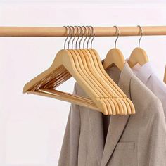 clothes hanging on wooden hangers in front of a white wall