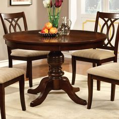 a dining table with four chairs and a bowl of fruit on it