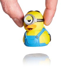 a hand holding a yellow toy in front of a white background