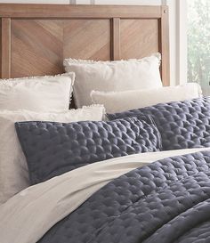 a bed with white pillows and blue comforter