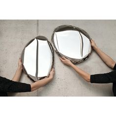 two women holding mirrors in their hands on the cement floor, with one looking at it's reflection