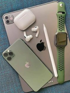 an apple watch, headphones, and other electronics are on the table next to each other