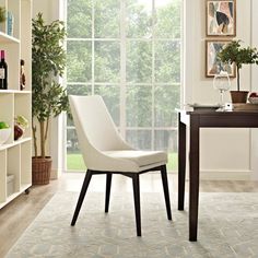 a white chair sitting in front of a window next to a desk and bookshelf