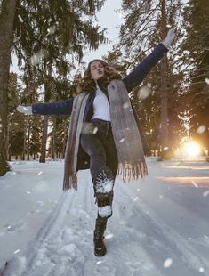 a woman is walking through the snow with her arms spread out and she has one leg in the air