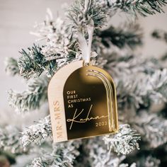 a personalized ornament hanging from a christmas tree with snow on the branches