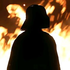 the silhouette of a person wearing a helmet in front of a fire