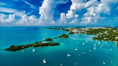 an aerial view of the ocean with boats in it and clouds over water behind them