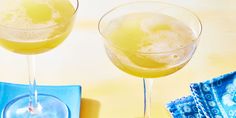 two glasses filled with yellow liquid sitting next to each other on top of blue napkins