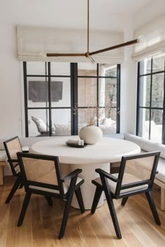 a white table with chairs around it in front of a large window and couches