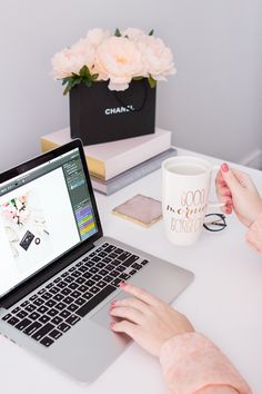 a woman sitting at a table with a laptop and coffee mug in front of her