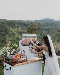 the bride and groom are getting ready to have their drinks at the outdoor bar with mountains in the background