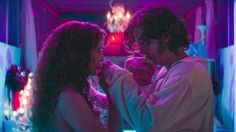 a man and woman standing next to each other in a room filled with christmas lights