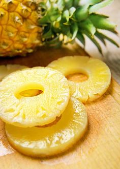 sliced pineapples on a cutting board next to a pineapple