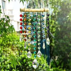 a wind chime hanging from a tree branch in the garden with beads and crystals