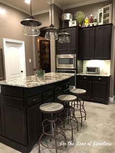 a kitchen with black cabinets and marble counter tops