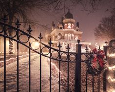 a gate that has some lights on it in front of a house with christmas decorations