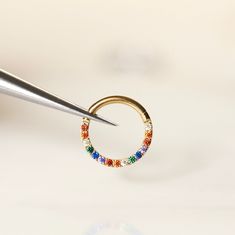 a pair of gold hoop earrings being worked on by a person using a needle to cut through the beading