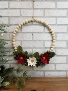 a wreath with poinsettis and greenery hanging on a brick wall