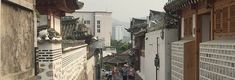 people are walking down an alley way with buildings on either side and in the distance