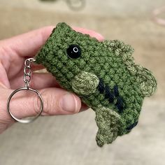 a crocheted frog keychain being held by someone