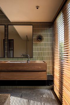 a bathroom with a sink, mirror and wooden slats on the wall in front of it