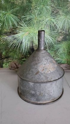 an old metal pot sitting on top of a counter next to a pine tree in front of a window