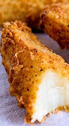 two pieces of fried food sitting on top of a white cloth covered in seasoning