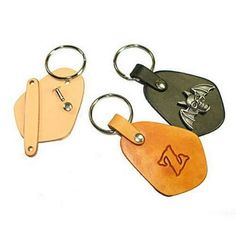 three leather keychains with different designs on them