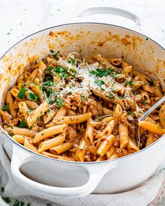 pasta with meat and parmesan cheese in a white pot on top of a cloth