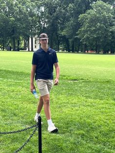 a man standing on top of a metal pole in a park next to a chain