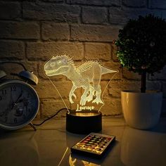 a light up dinosaur on a table next to an alarm clock