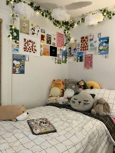 a bed with stuffed animals on it in a room decorated with posters and garlands