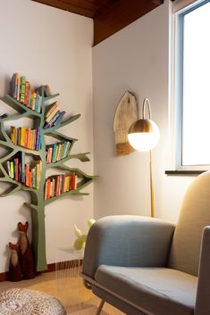 a living room filled with furniture and a tree shaped book shelf next to a window