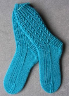 a pair of blue knitted socks laying on top of a gray surface next to each other