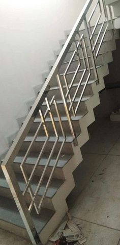 a white staircase with metal handrails next to a trash can on the ground