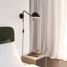 a bed with white sheets and a black lamp next to it on a bedside table