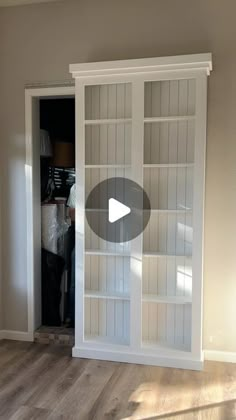 an empty room with white bookcases and wood floors