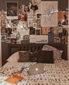 a bed with many pictures on the wall and a laptop computer sitting on top of it