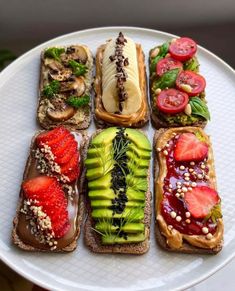 a white plate topped with sandwiches covered in fruit and vegtables on top of each other