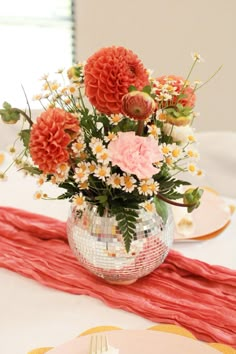 a vase filled with flowers sitting on top of a white tablecloth covered dining room table