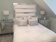 a bed with white sheets and pillows in a room