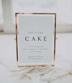 a sign that says let's eat cake on top of a white table cloth