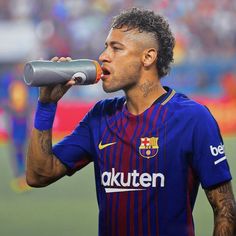 a soccer player drinking from a green cup