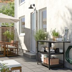 an outdoor patio with potted plants and chairs on the side walk way next to a building