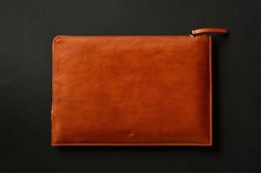 a brown leather pouch sitting on top of a black table next to an orange object