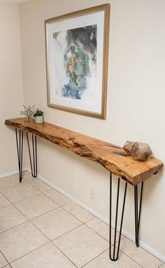 a long wooden table with hairpin legs in a room next to a painting on the wall